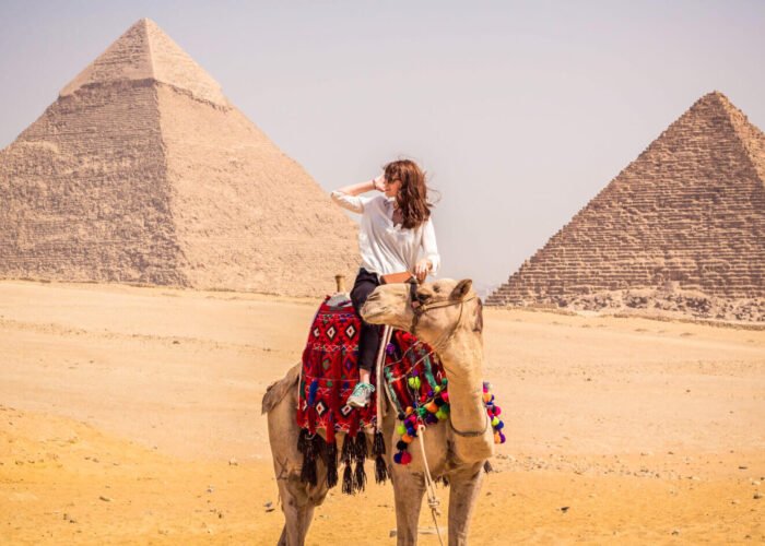 A tourist riding a camel in front of the pyramids