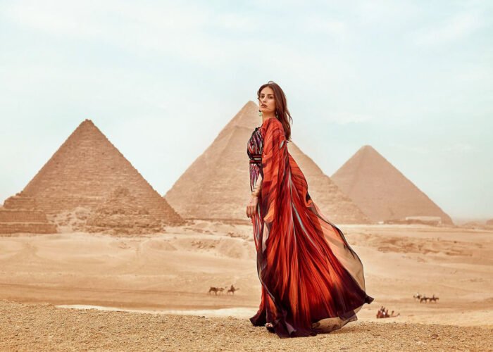 A wonderful picture of a girl wearing a red dress standing in front of the pyramids