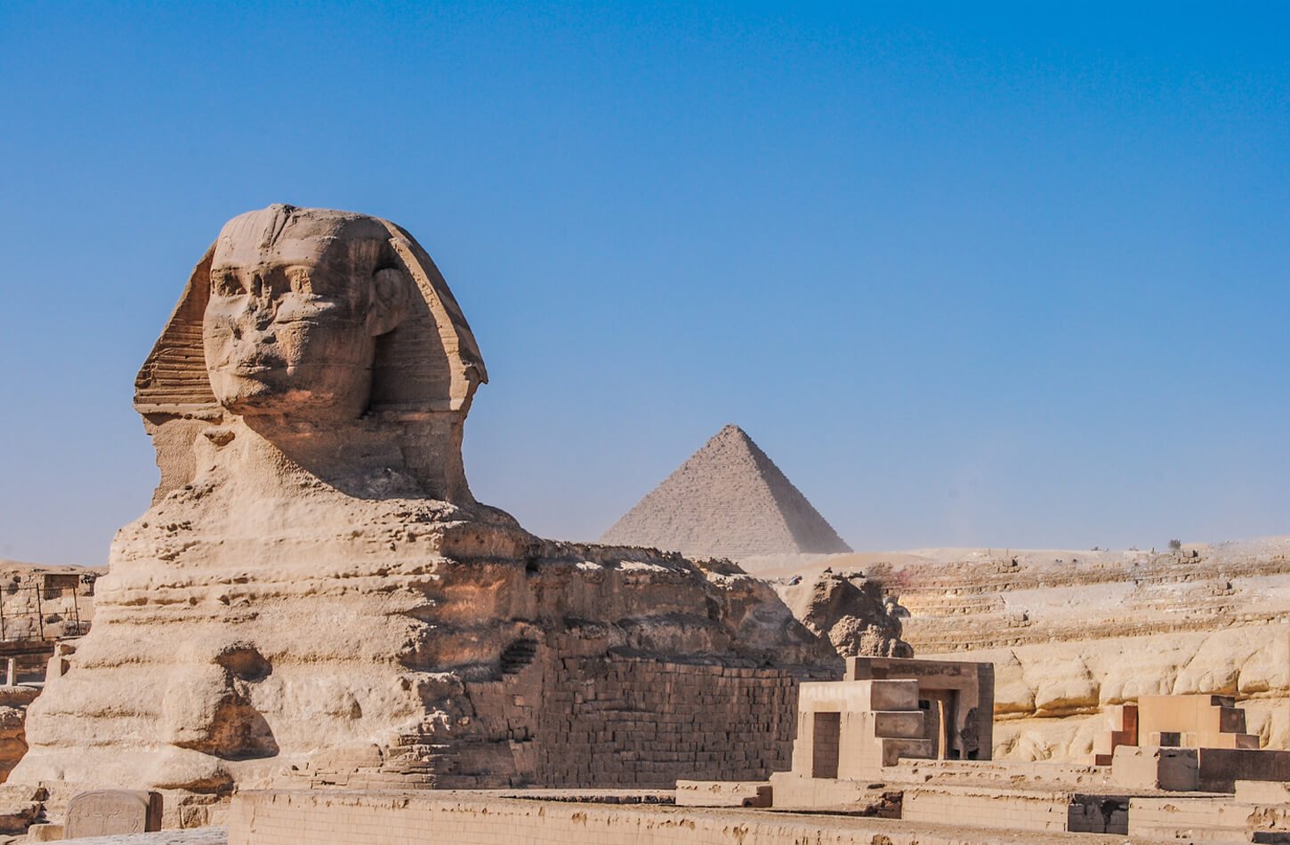 The Great Sphinx of Giza with a large pyramid in the background, a prime example of architectural engineering when looking at how ancient Egyptians built the pyramids.