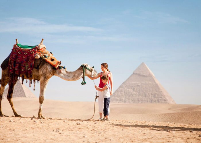 Wonderful picture of a little boy and his mother with a camel in front of the pyramids