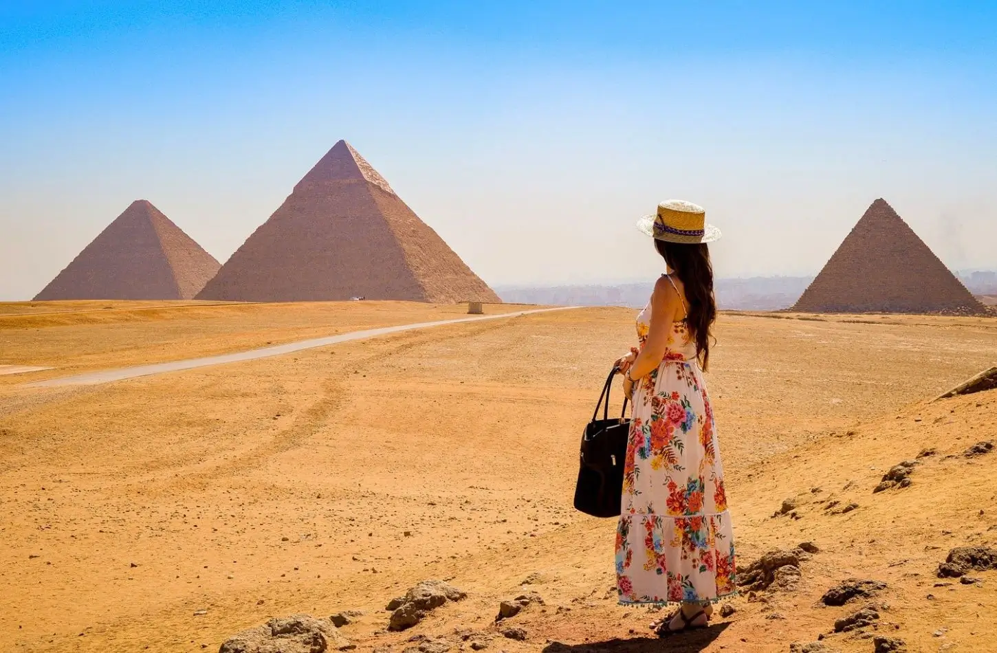 Egypt Travel Tips from Locals: woman in floral dress looks at the Giza Pyramids.