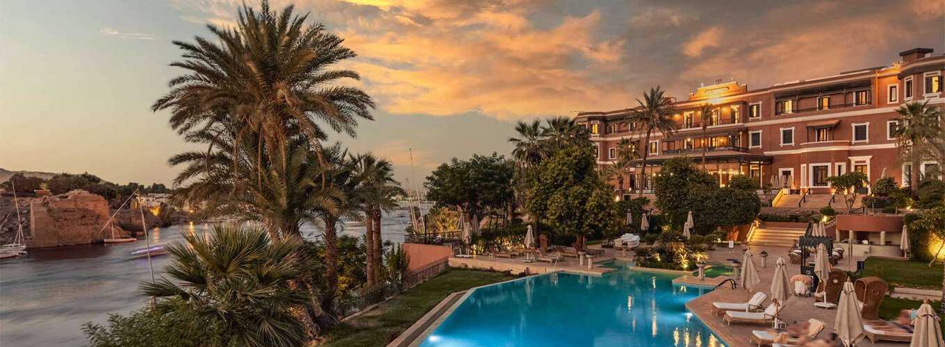 Luxury hotel in Aswan, Egypt, with large swimming pool and palm trees at sunset. Luxury hotel in Aswan, Egypt, with large swimming pool and palm trees at sunset