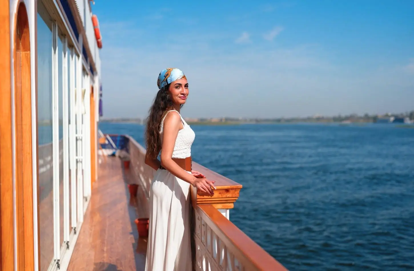 Woman enjoying a scenic view from a boat deck, highlighting the best time for a Nile cruise in Egypt for pleasant weather