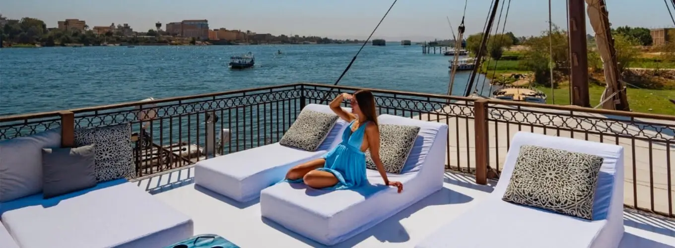 A-stunning-photo-of-a-tourist-sitting-on-a-sofa-on-the-deck-of-the-cruise-ship. Tourist in a blue dress relaxing on the sun deck lounge of a Nile River cruise ship.