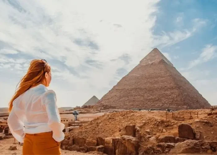 A solo female traveler looking at the Great Pyramid of Giza, a highlight of any Egypt itinerary 7 days.