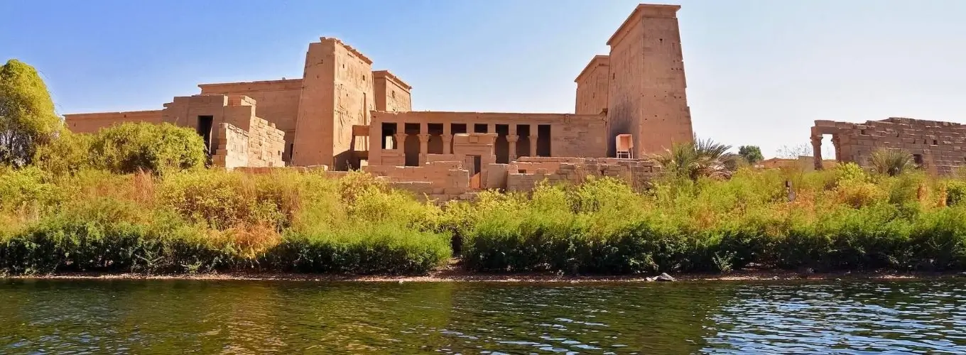 amazing-nile-river-view-philae-temple-aswan-egypt Panoramic view of the ancient Egyptian Philae Temple complex on Agilkia Island, seen from the Nile River in Aswan under a clear blue sky.