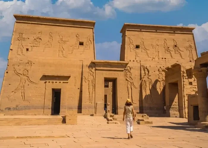 Tourist exploring the sunny Philae Temple in Aswan under clear blue skies during a trip to Egypt in February.