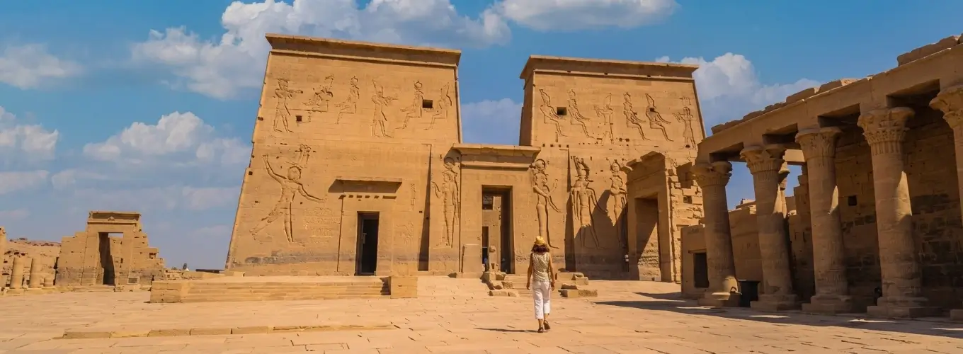 Tourist exploring the sunny Philae Temple in Aswan under clear blue skies during a trip to Egypt in February.